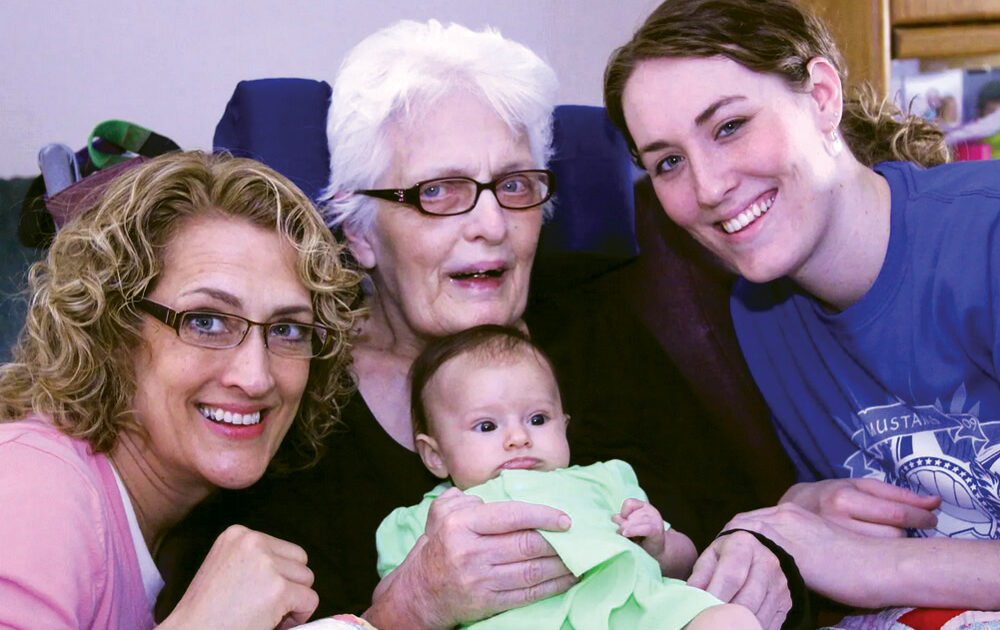A group of women holding a baby and smiling.