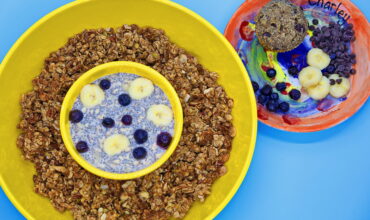 A bowl of cereal and a plate with fruit.
